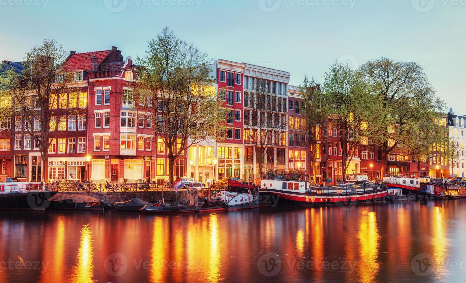 Canal houses of Amsterdam at dusk with vibrant reflections, Neth photo