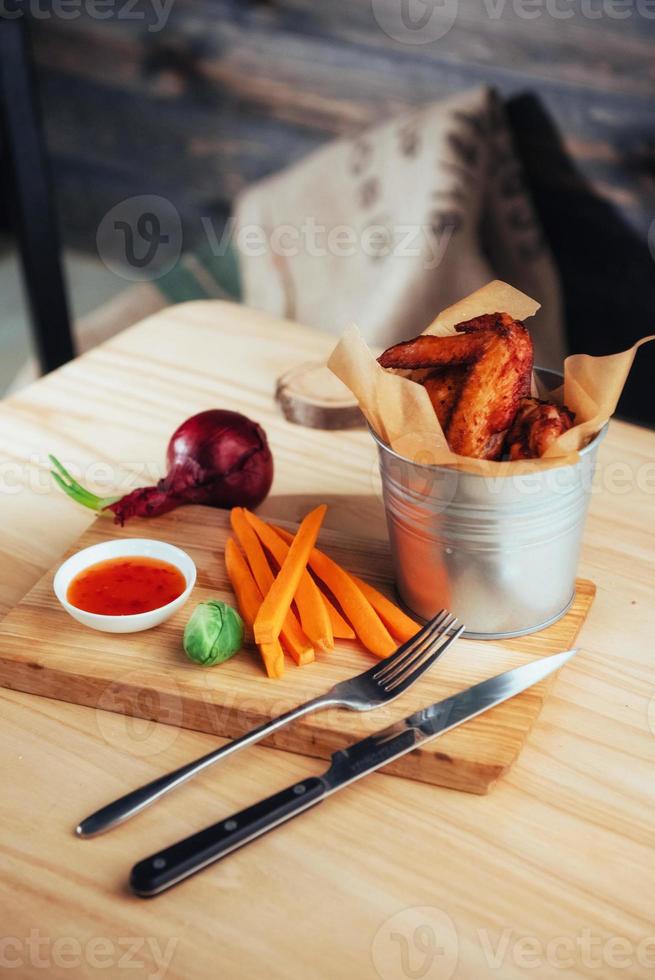 alitas de pollo adornadas con salsa y verduras sobre mesa de madera foto