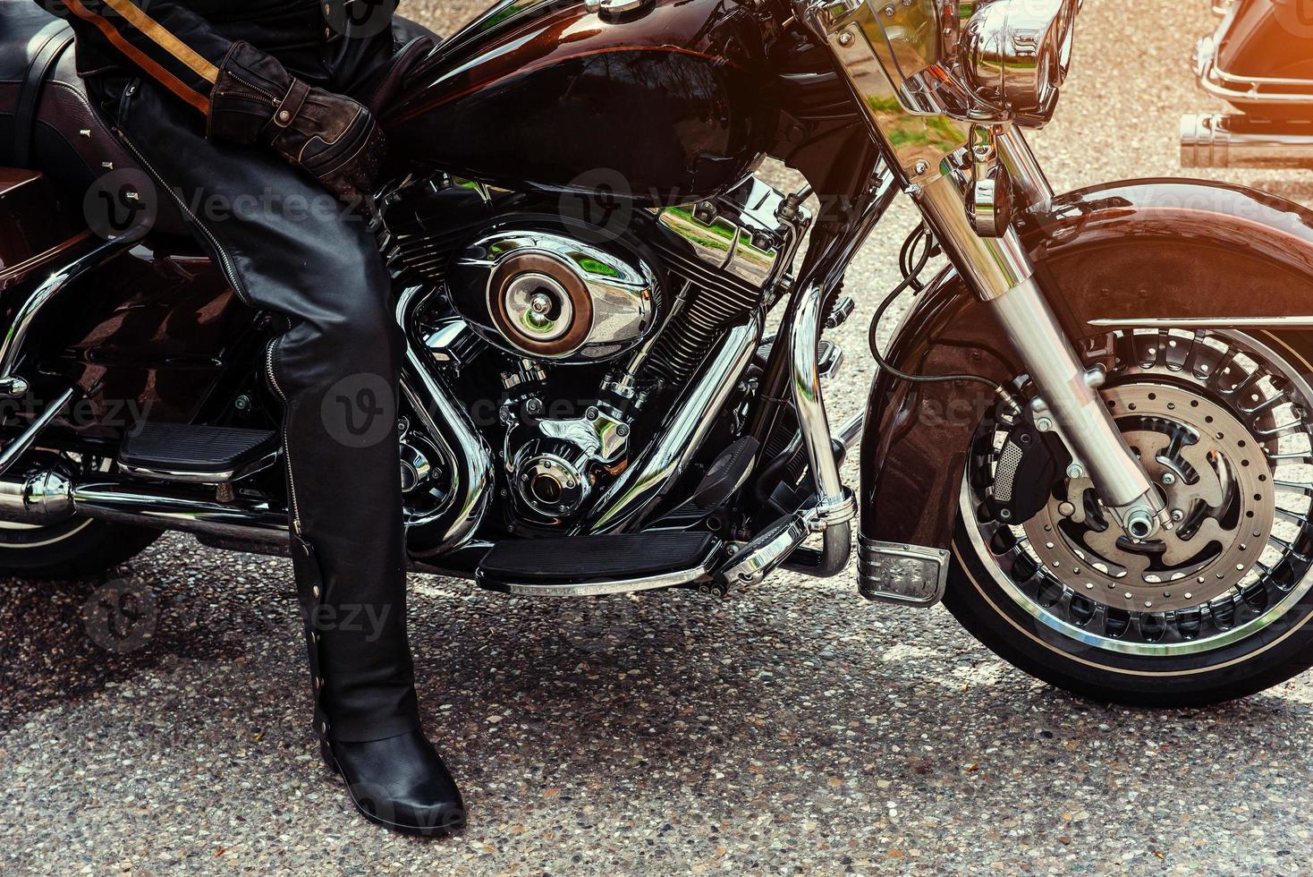 motorista con botas negras sentado en una motocicleta foto