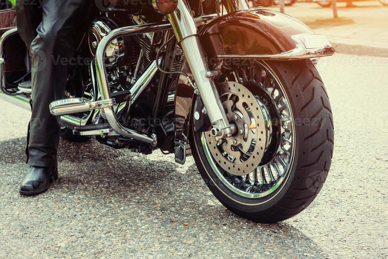 Biker in black boots sitting on a motorcycle photo