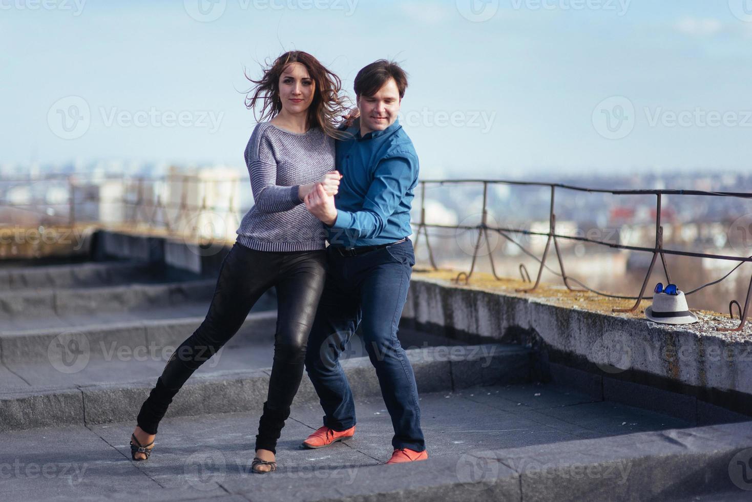 pareja joven bailando en el techo de un edificio alto foto