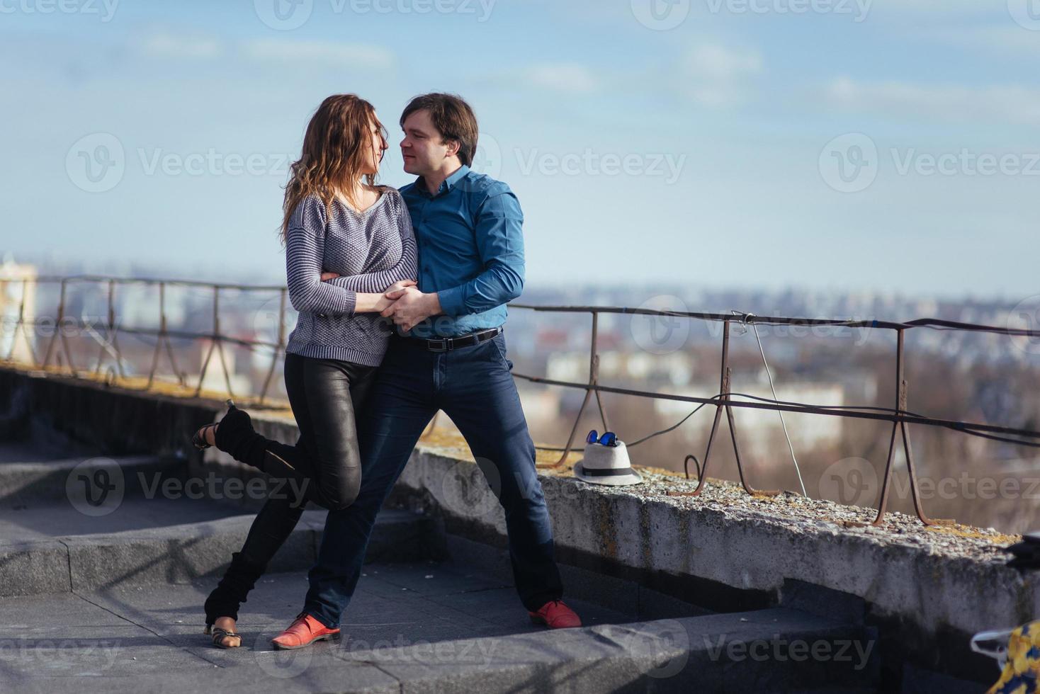 young couple dancing on the roof of a tall building photo