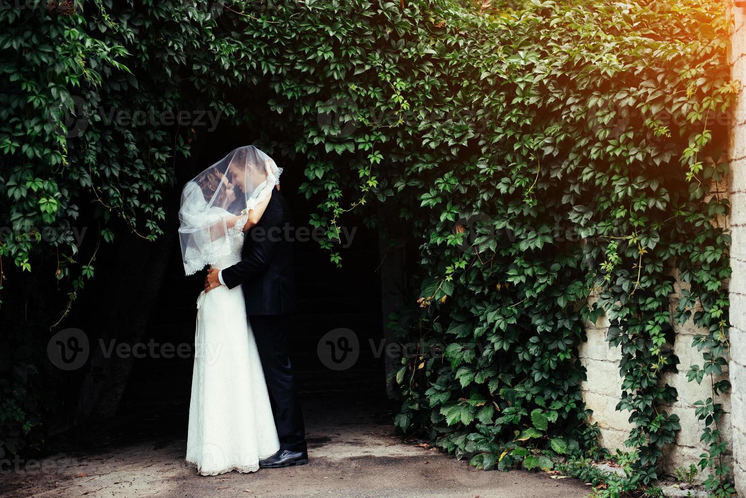 hermosa joven pareja de novios besándose, novia rubia con flores foto