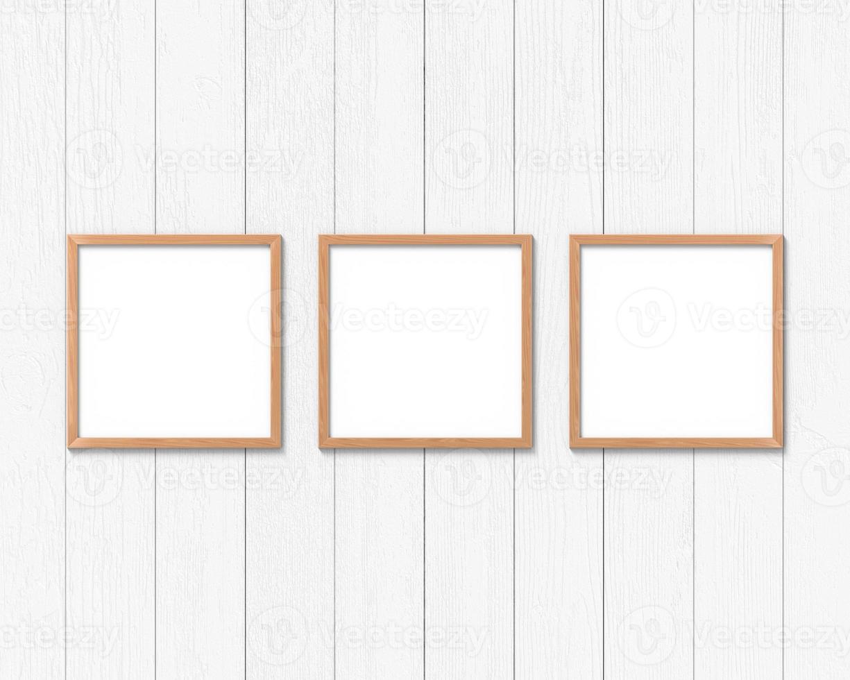 conjunto de 3 maquetas de marcos de madera cuadrados colgados en la pared. base vacía para imagen o texto. representación 3d foto