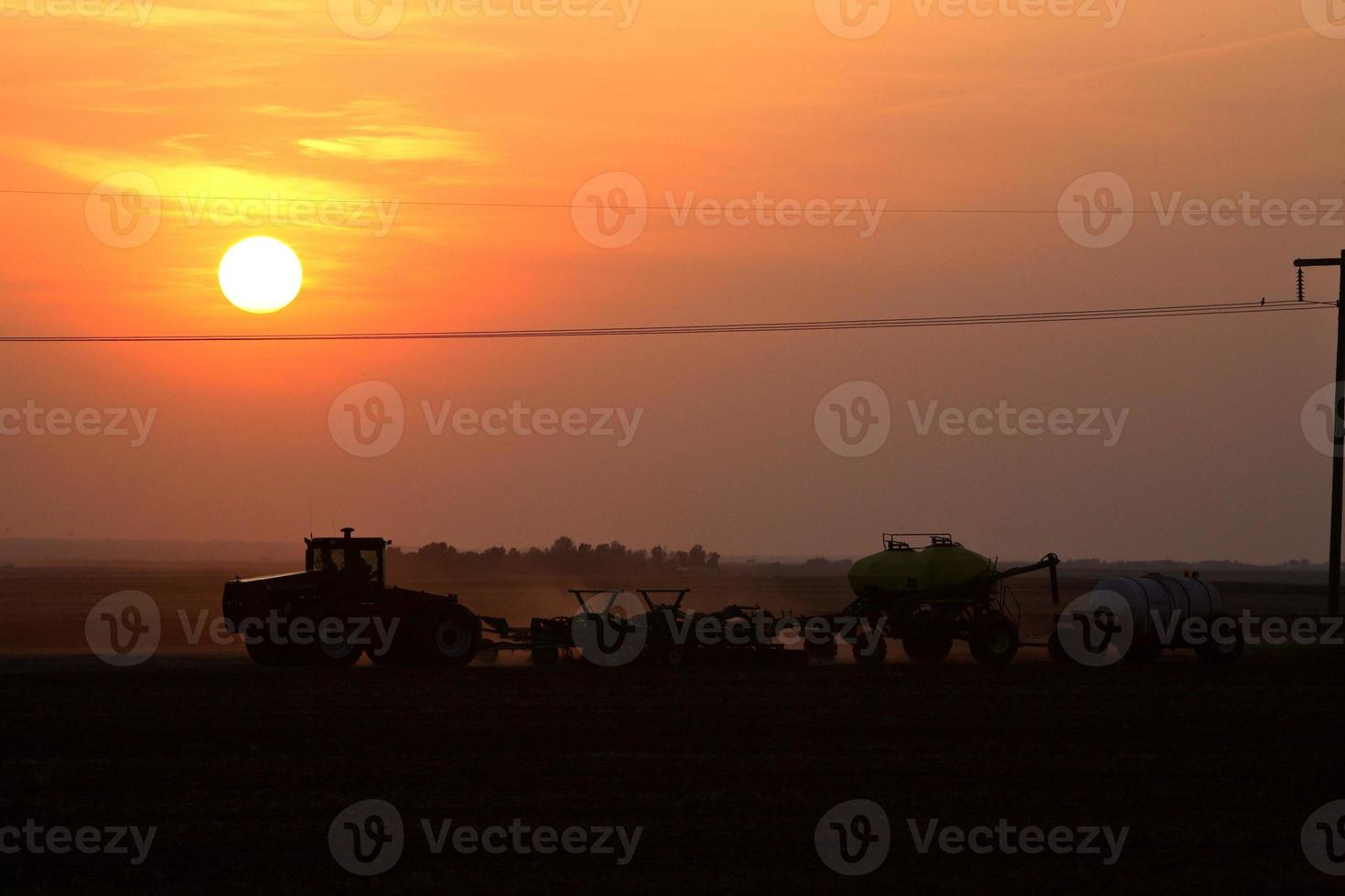 puesta de sol detrás de un agricultor de saskatchewan sembrando foto