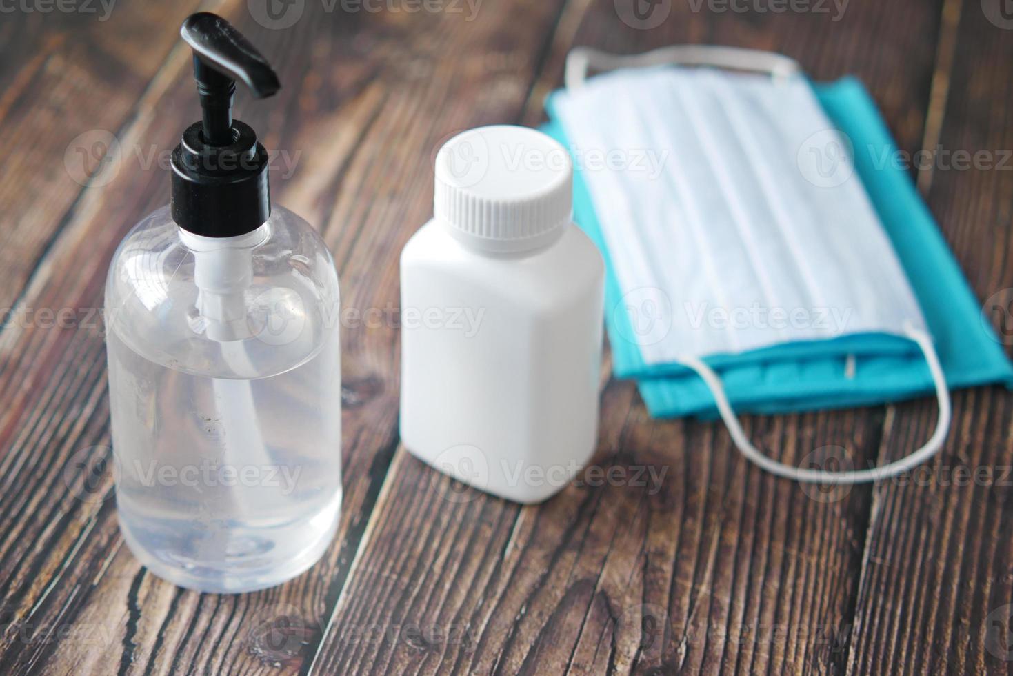 Surgical masks, medical gloves and hand sanitizer on wooden background photo