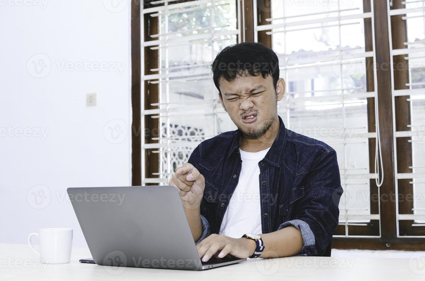 Young Asian man angry and mad what he see in the laptop when work photo