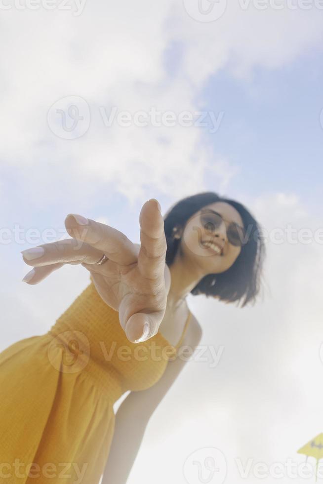 retrato de una mujer asiática feliz y sonriente con vistas al cielo azul desde abajo. foto