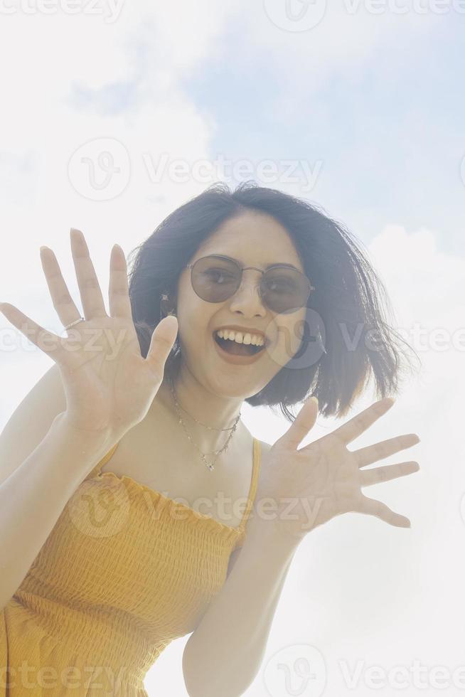 retrato de una mujer asiática feliz y sonriente con vistas al cielo azul desde abajo. foto