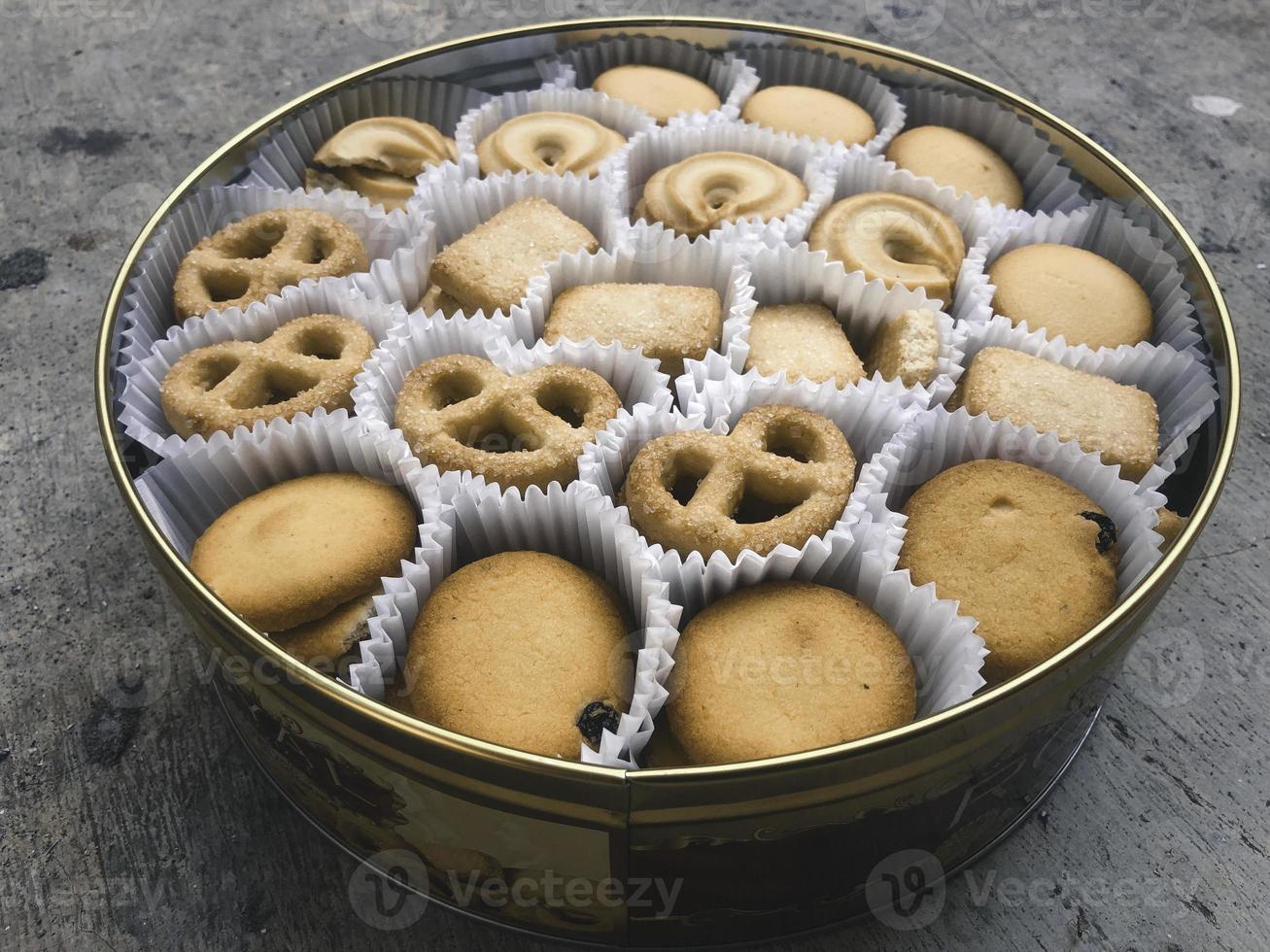 An overhead photo of a tin can of Danish butter cookies, shot from above on a light background texture with a place for text