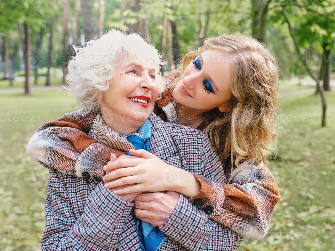 senior woman with young daughter walking outdoor in spring. Family, generation, care, love, vaccination concept photo