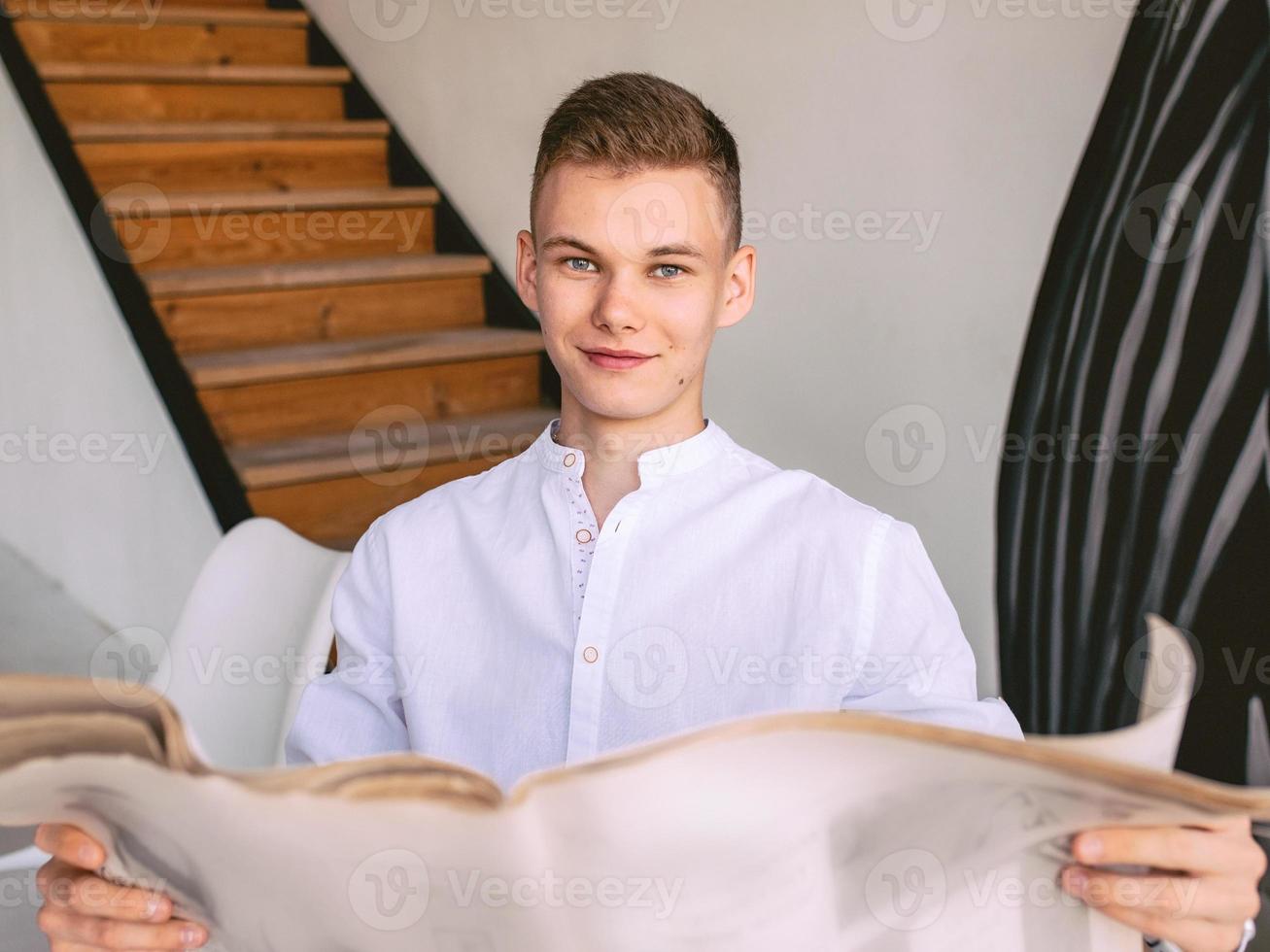 Modern teen man reading paper newspaper while breakfast at home. Reading, old fashion, modern, news concept photo