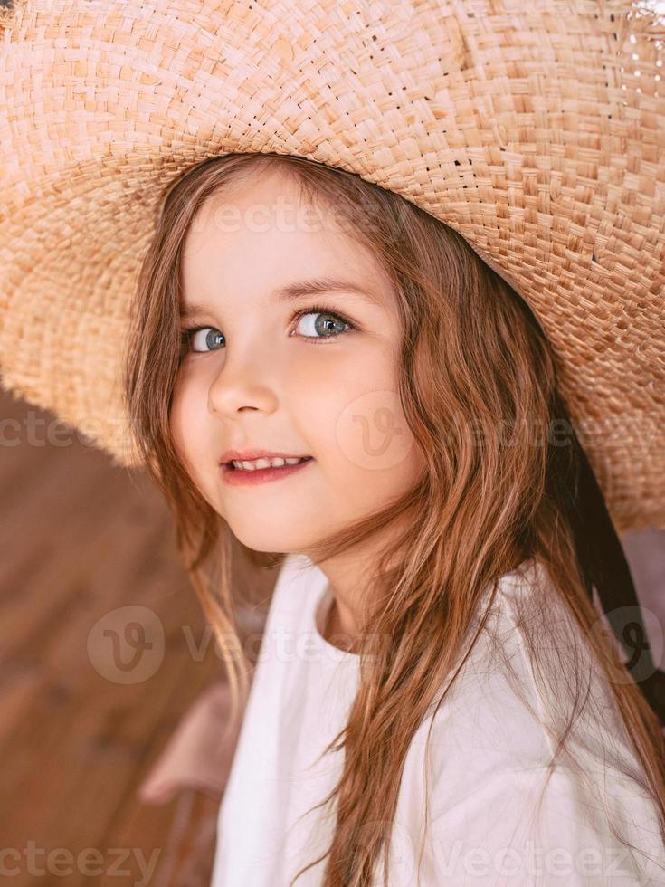 adorable niña alegre con sombrero de paja en casa interior. moda, estilo, infancia, emociones, concepto de crecimiento foto