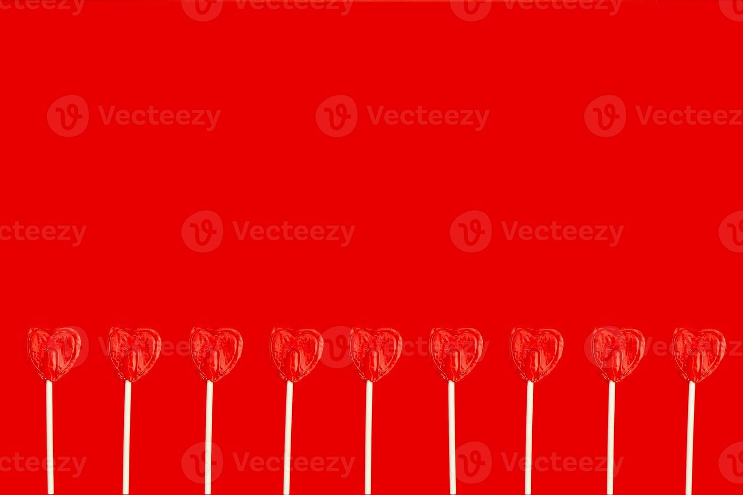 various heart shaped lollipops side by side on a red background with copy space photo