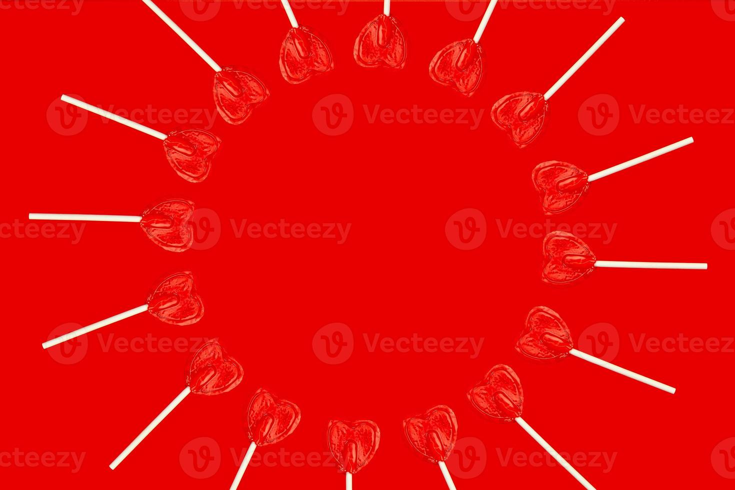 several heart shaped lollipops placed side by side forming a circle on a red background. photo