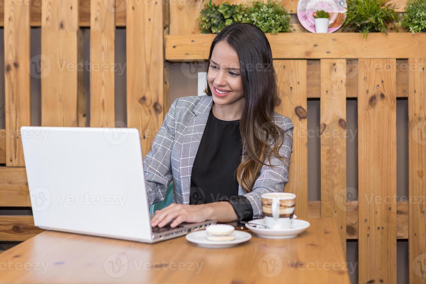 mujer sonriente escribiendo en la computadora portátil y tomando café y postre foto