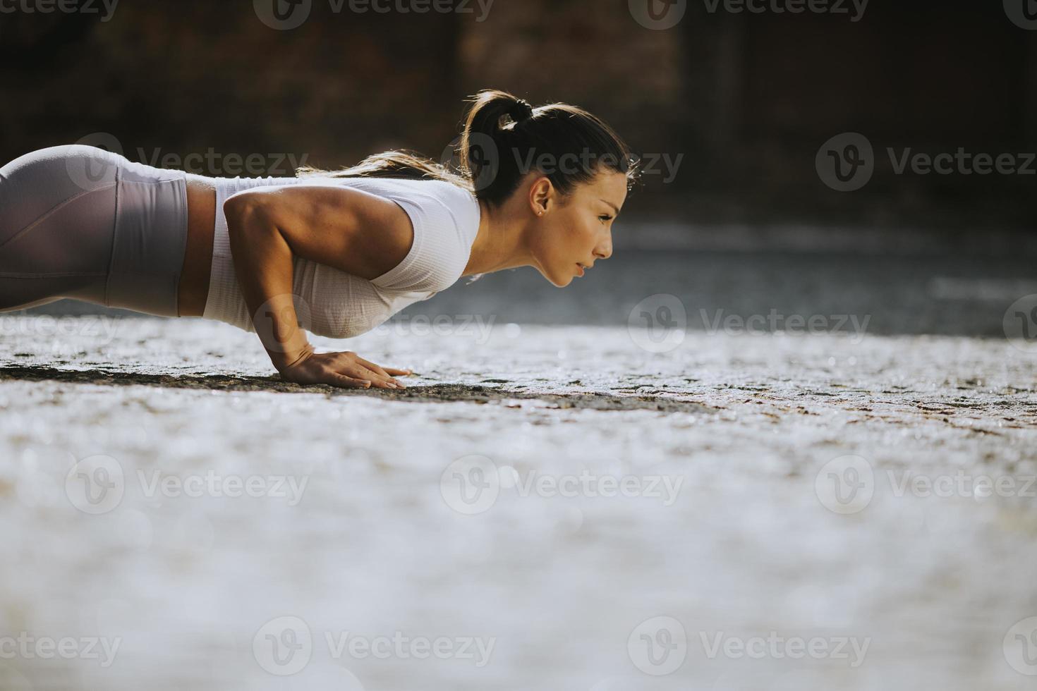 Young woman doing puhsups on the street photo