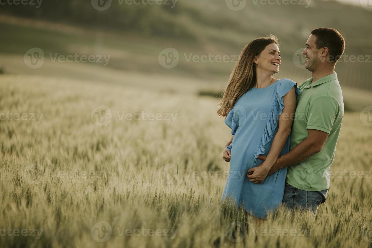 joven esposo y su esposa embarazada en el campo de verano foto
