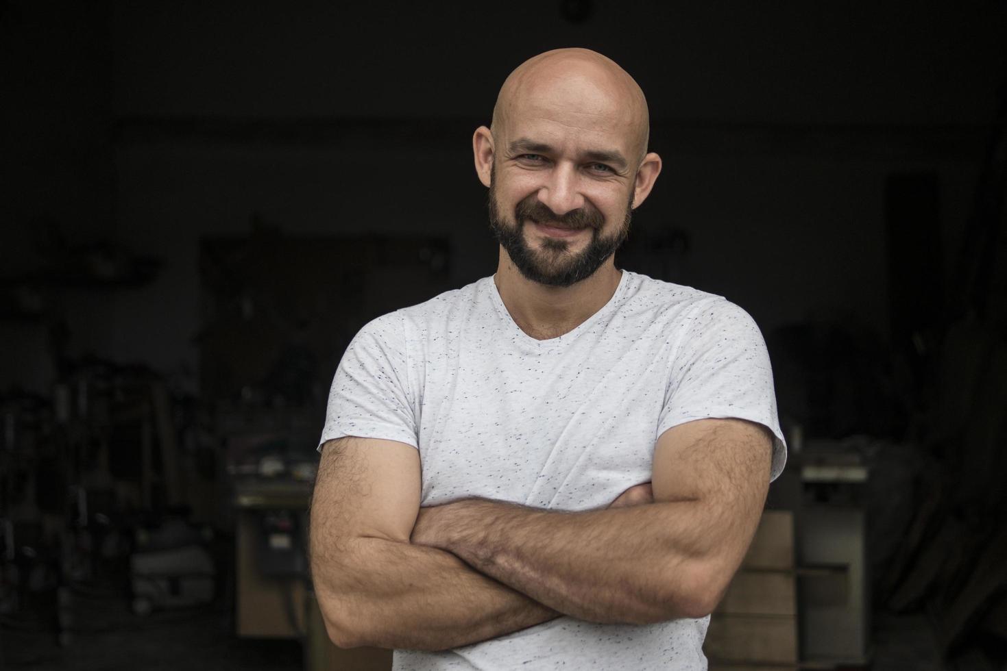 retrato de carpintero calvo blanco con barba en camiseta blanca. aislar sobre un fondo negro foto