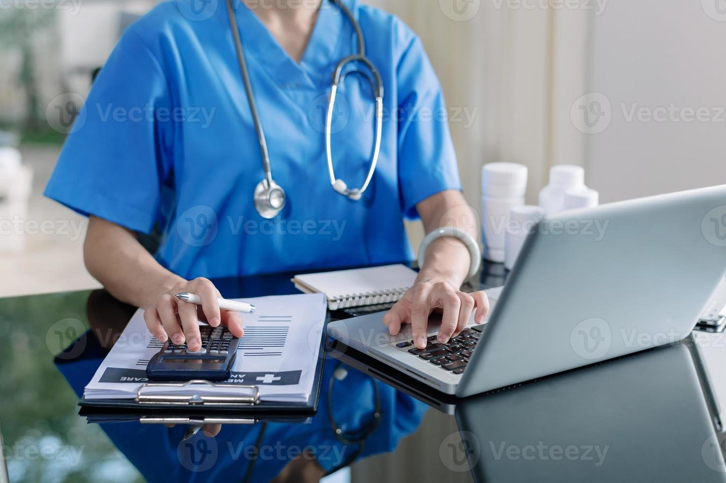 Healthcare costs and fees concept.Hand of smart doctor used a calculator and smartphone, tablet for medical costs at hospital photo