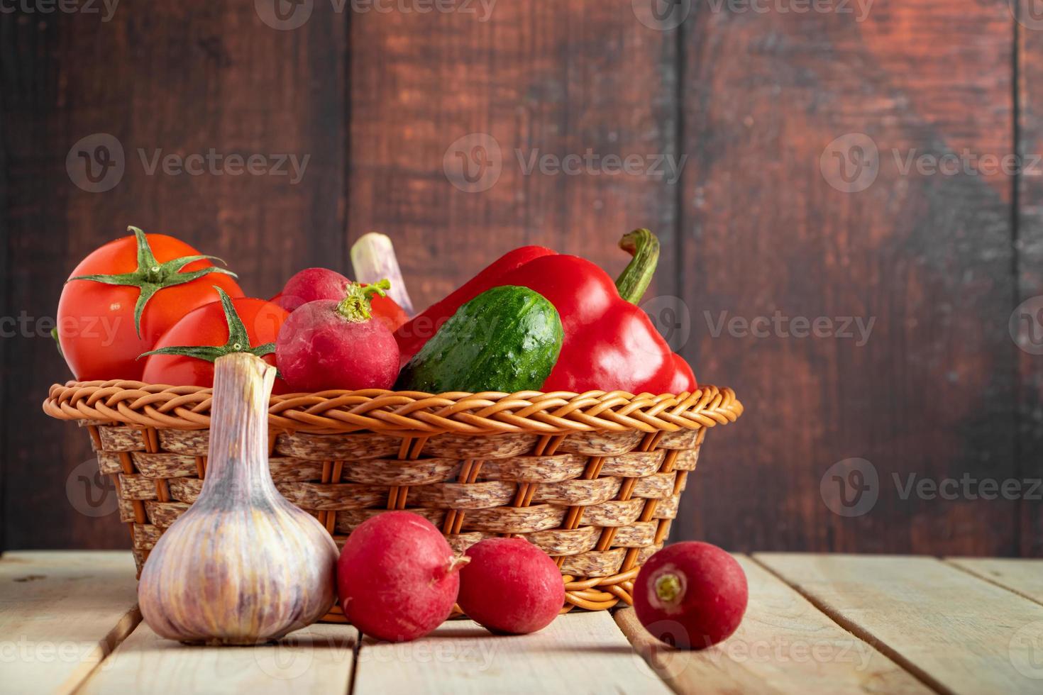 Set of fresh vegetables in a basket on a wooden background. photo