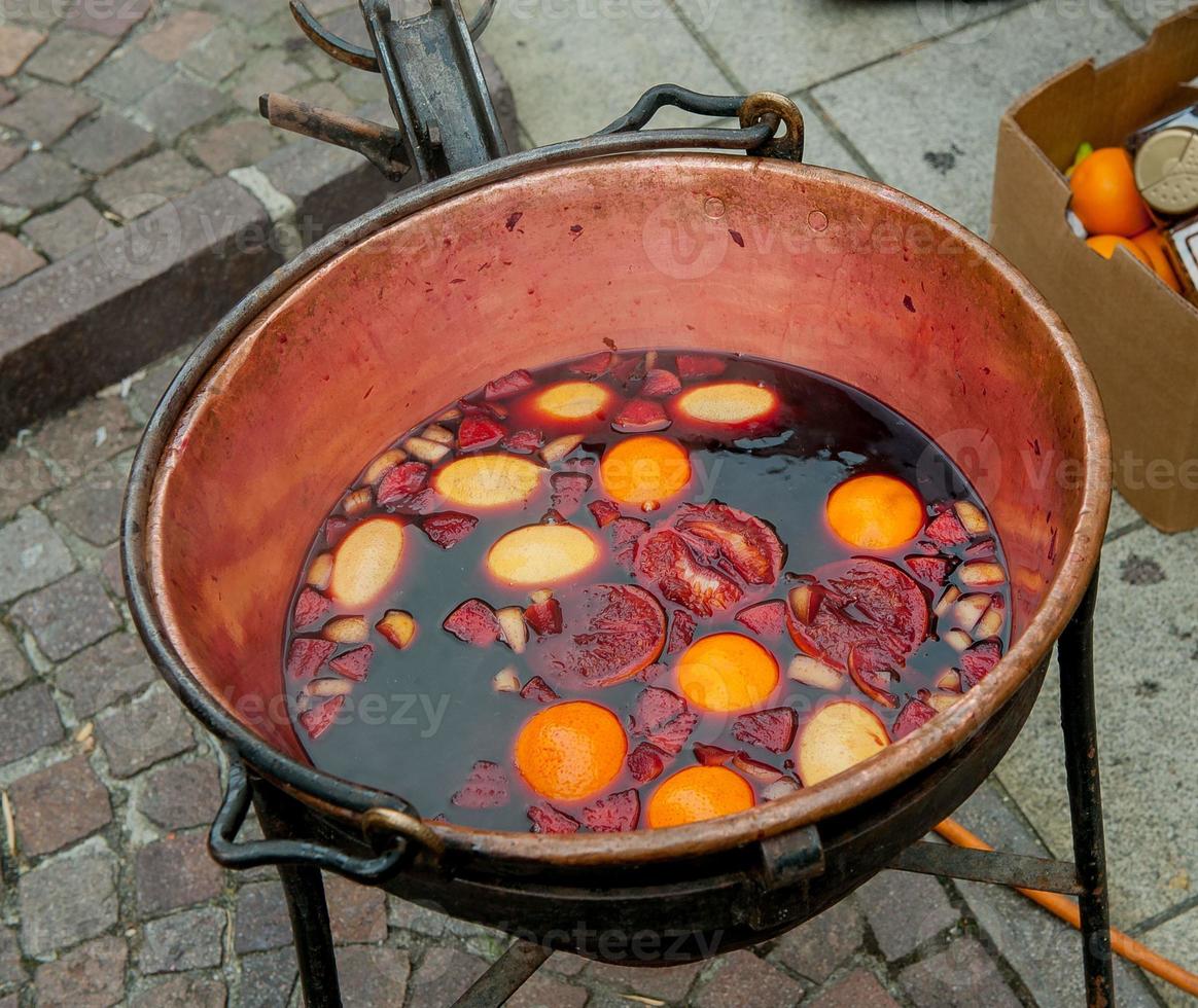 olla de cobre con vino caliente y fruta foto