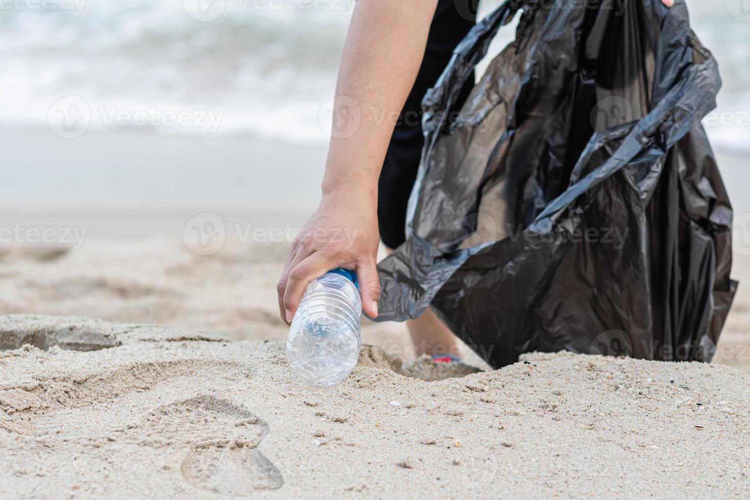 Woman cleans up by picking up plastic bottles at the beach. Concept of protecting the environment, saving the world, recycling, reducing global warming. closeup, blurred background, copy space on left photo