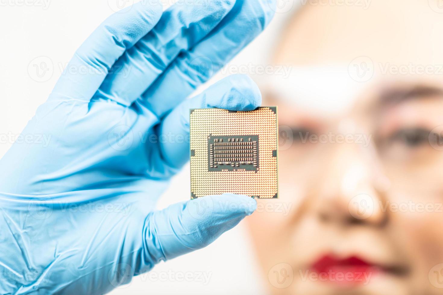 A female engineer working in a lab wearing protective goggles and gloves holds the new processor in her hands and examines it. Scientist holding chipset in laboratory Computer concepts, hardware, fix photo