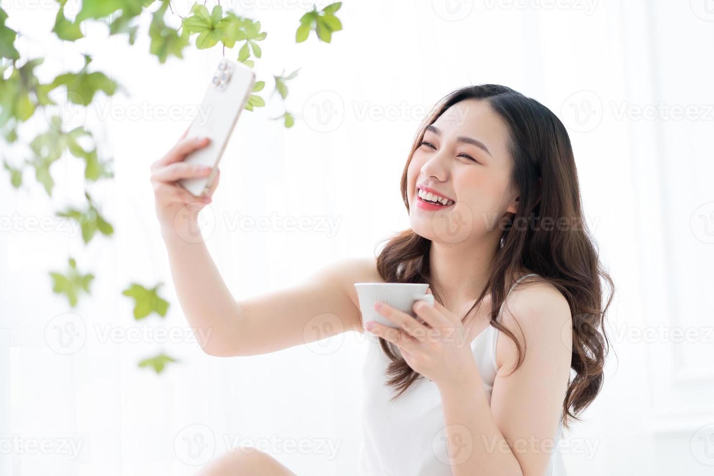 joven asiática usando un teléfono inteligente en casa por la mañana foto