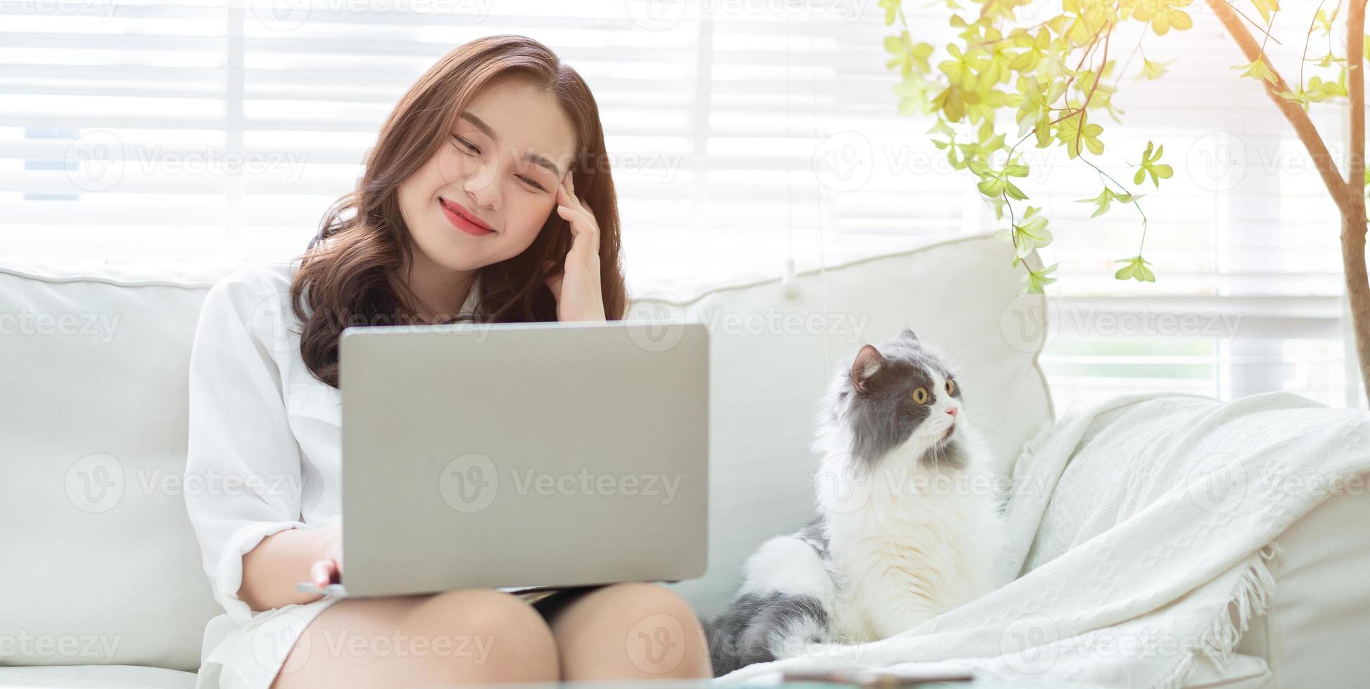 joven empresaria asiática trabajando y jugando con gato foto