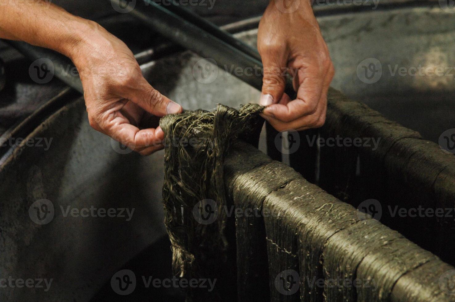 painting threads and yarns. male hands paint the cloth in the trough photo