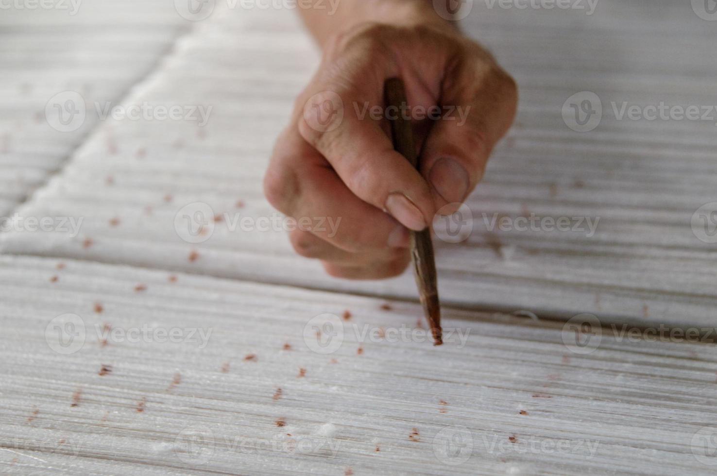 hand with a pencil makes marks on the carpet. weaving and manufacturing of handmade carpets closeup photo