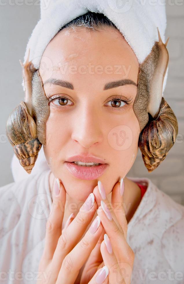 portrait of young dark haired woman with snails achatina giant on her face photo