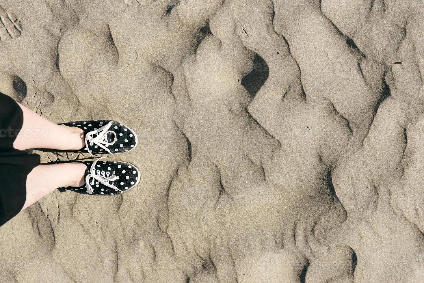 feet in polka dots shoes on the sand in desert photo