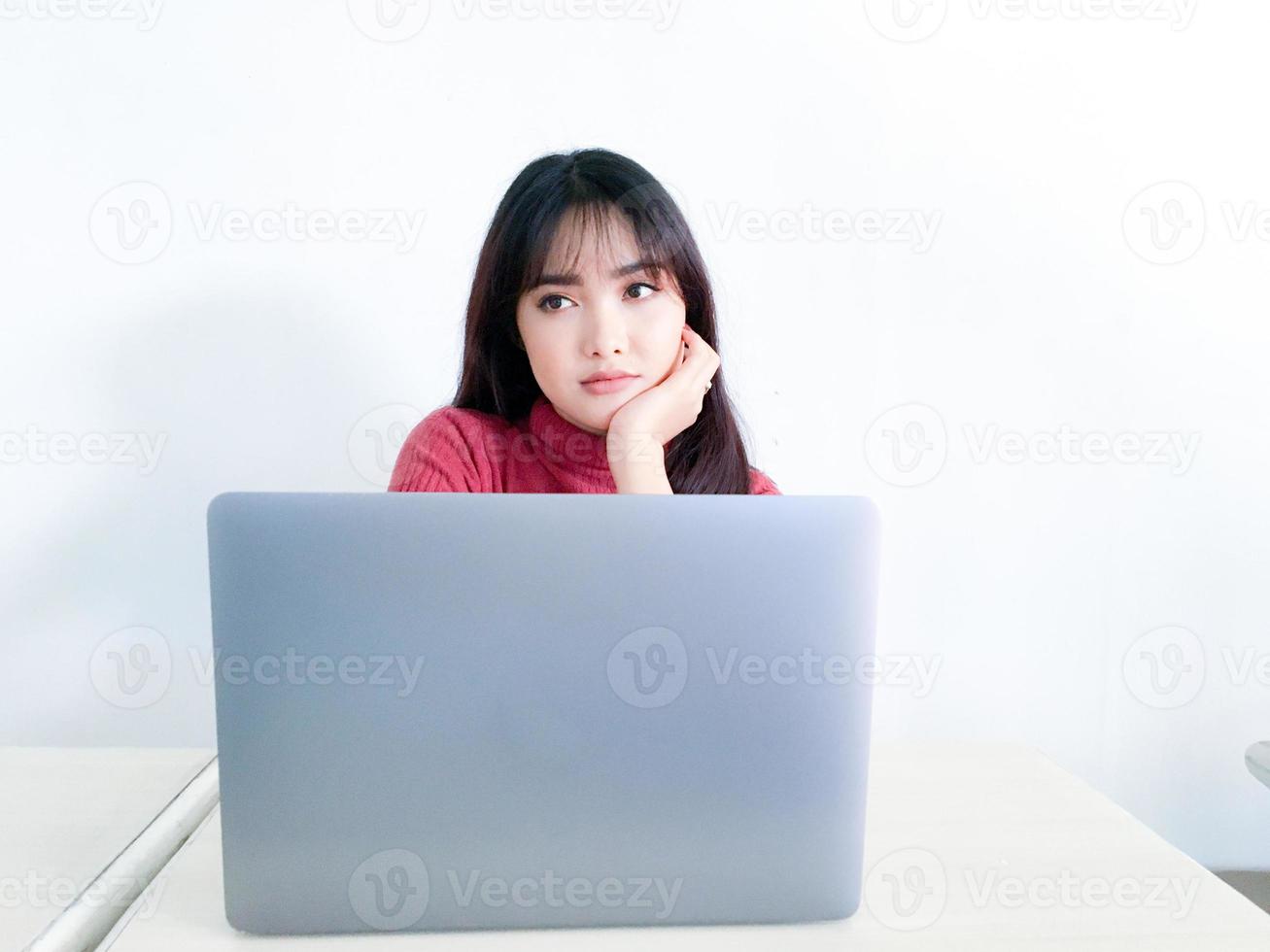 Asian beautiful hair girl is confuse or bored in the front of laptop on the isolated white background photo