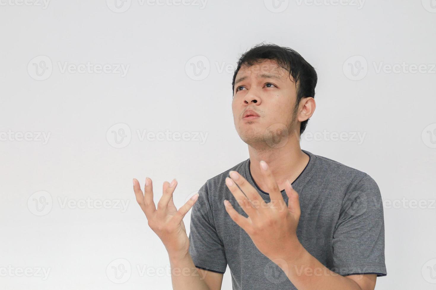 Young Asian man in gray t-shirt praying with sad face photo