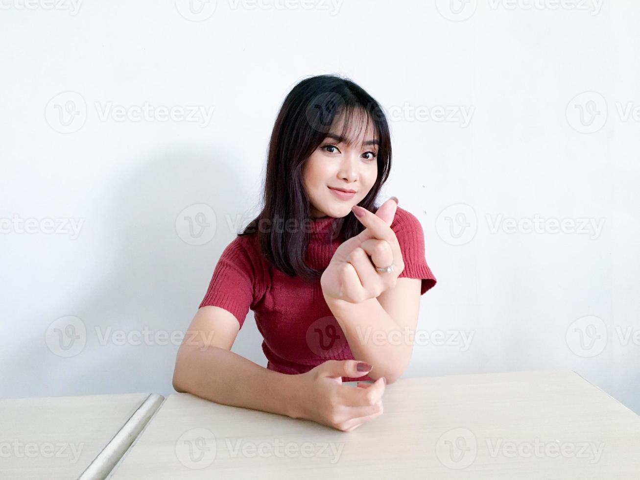 Asian beautiful smiling girl showing love korea sign with finger with blurred background isolated white background. Indonesian Women photo