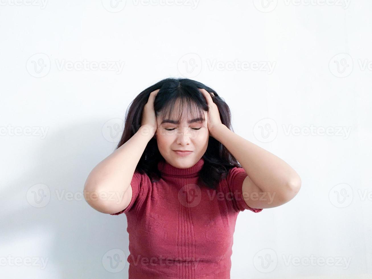 retrato de una mujer joven estresada sosteniendo la cabeza en las manos con el fondo. niña asiática infeliz con expresión de cara preocupada y estresada mirando hacia abajo. foto