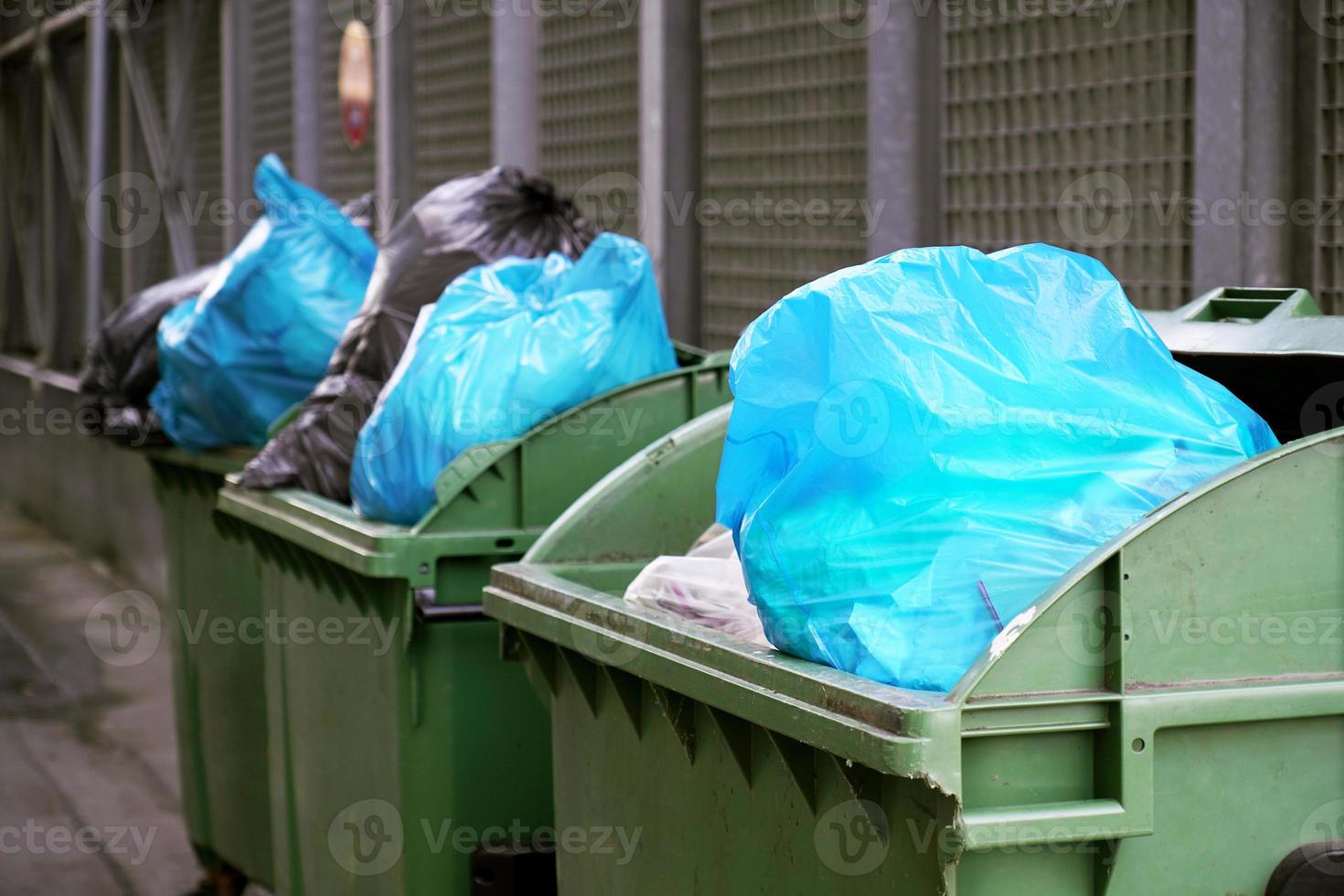 dumpster or refuse container overflowing with trash in garbage bags photo