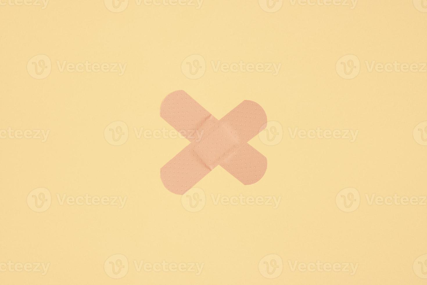 two strips of adhesive plaster tape on skin colored paper background photo