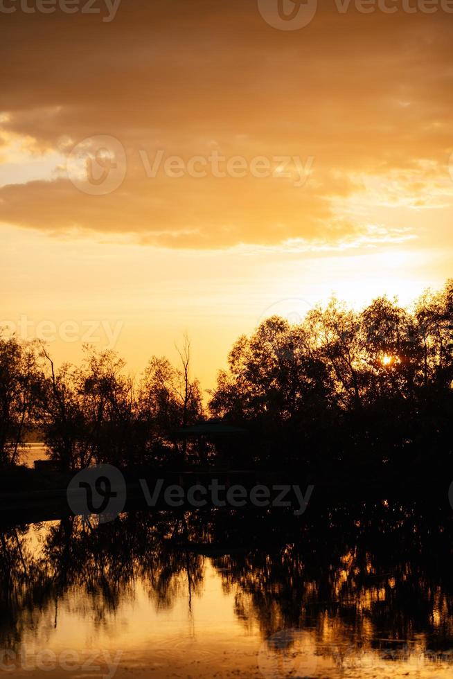 puesta de sol naranja en el río con siluetas foto