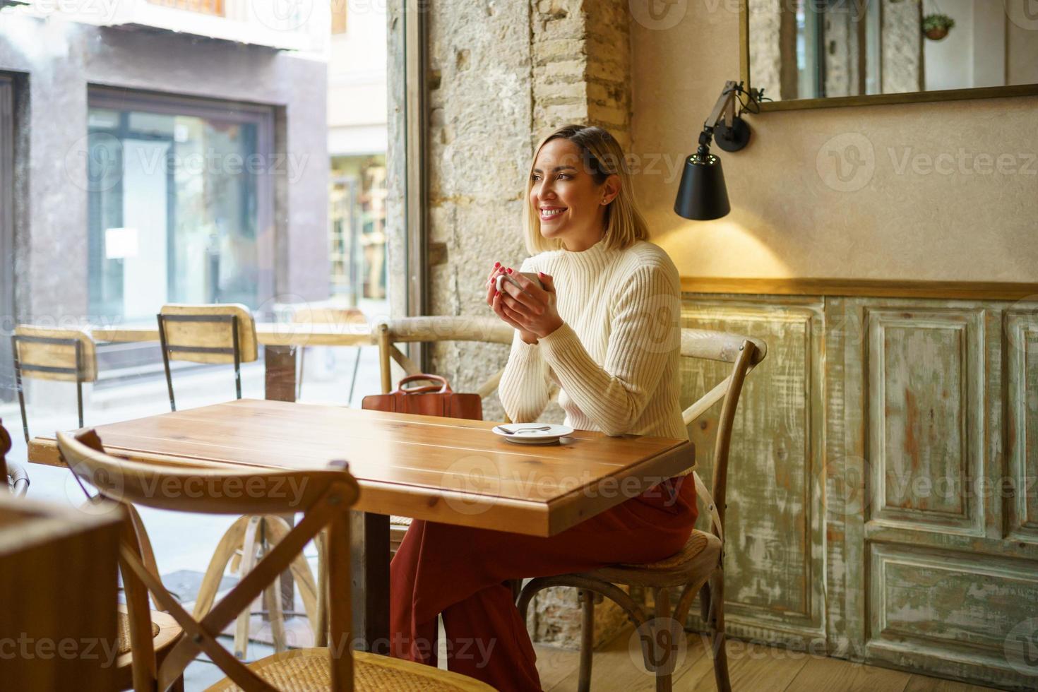 Delighted woman with coffee in cafe photo