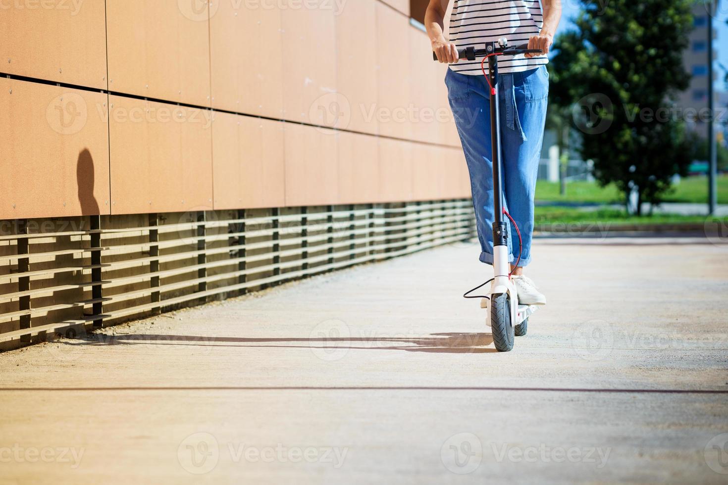 mujer circulando por la ciudad con un scooter eléctrico foto