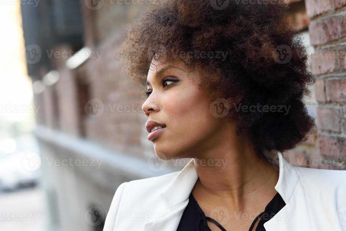 joven mujer negra con peinado afro de pie en el fondo urbano foto