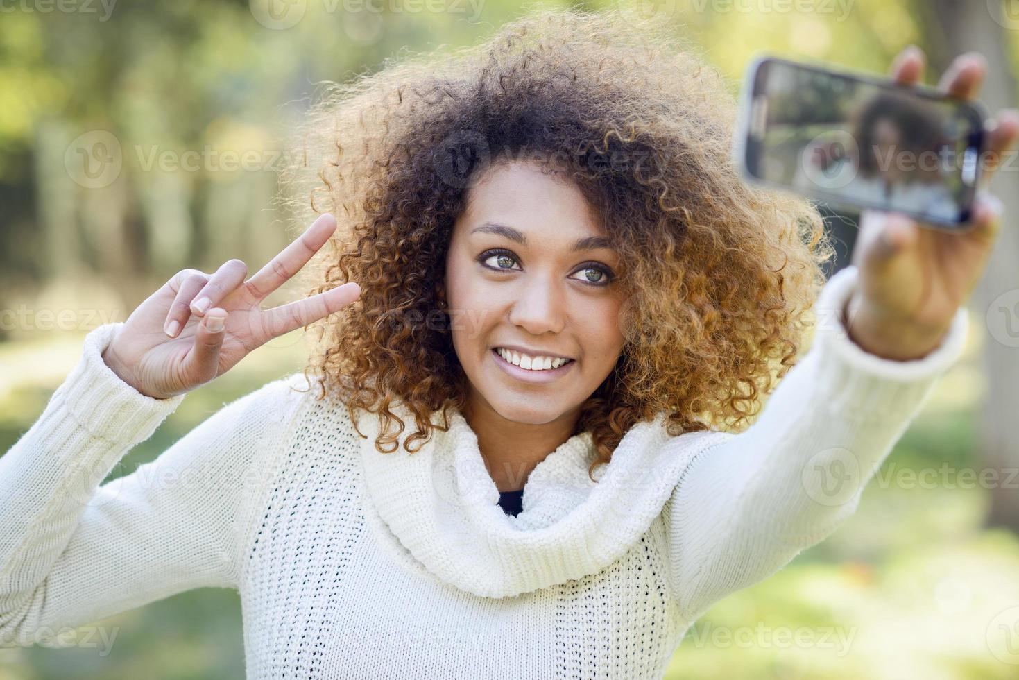 joven afroamericana selfie en el parque con un teléfono inteligente foto