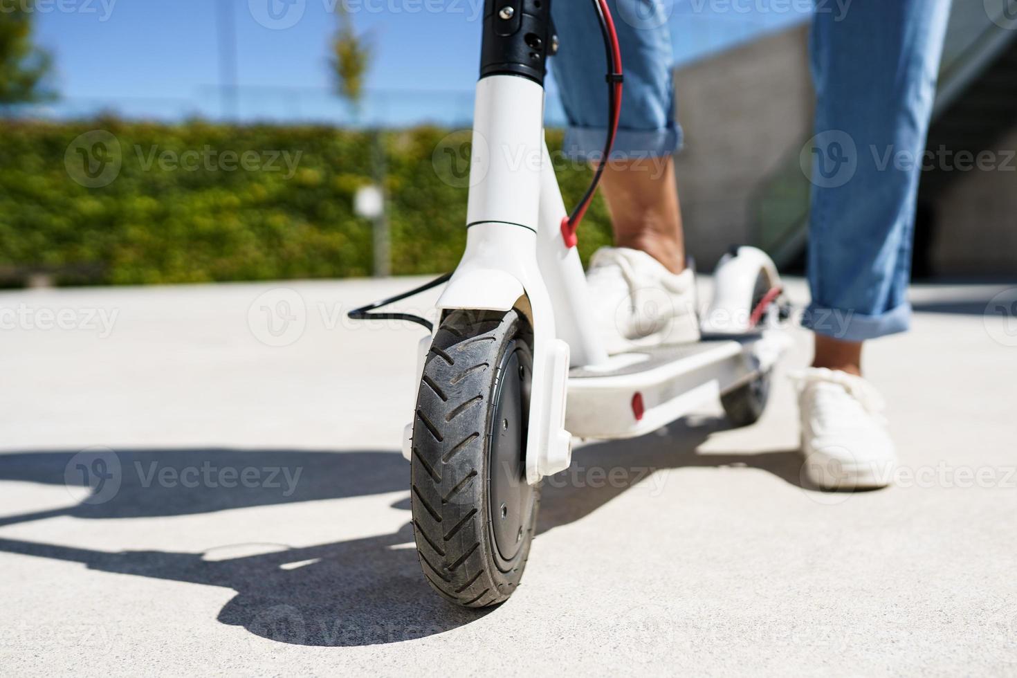 mujer circulando por la ciudad con un scooter eléctrico foto