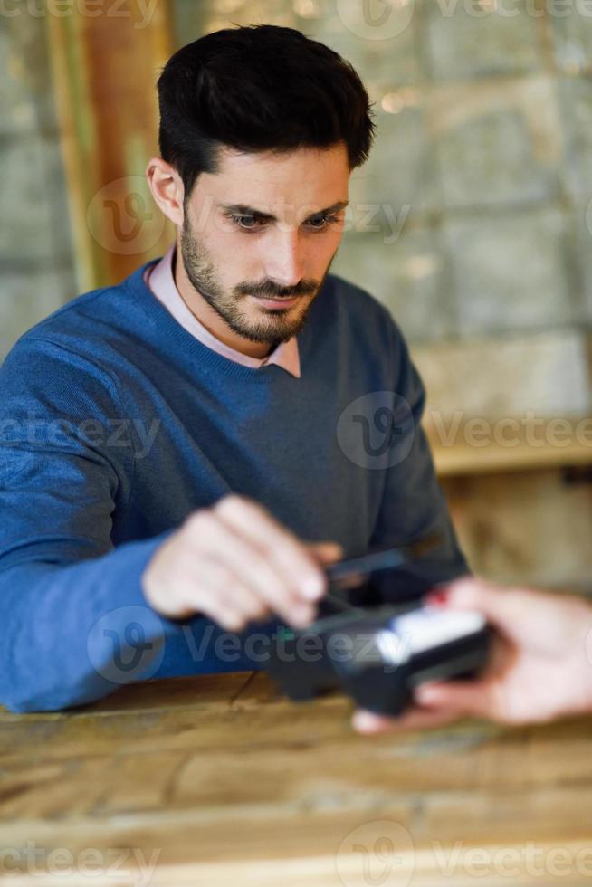 mano que sostiene el teléfono inteligente pagando en la máquina edc. foto