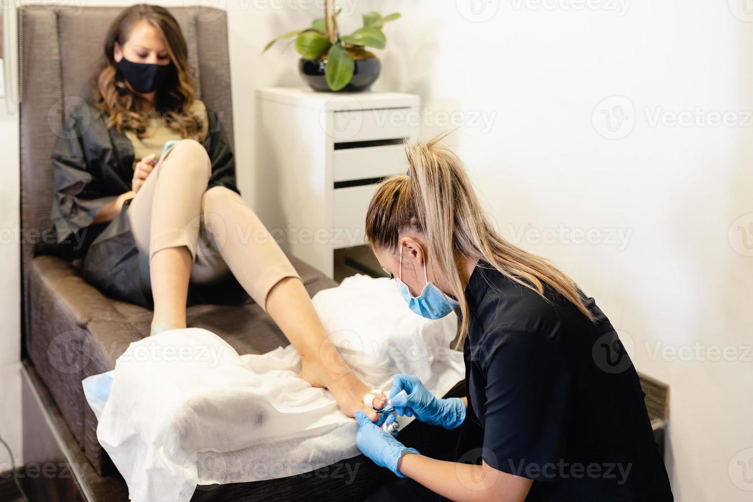 esteticista dando una pedicura limando las uñas a un cliente en un centro de belleza. foto