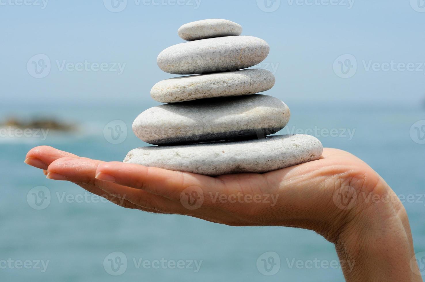 Gravel pile in woman's hands with sea background photo