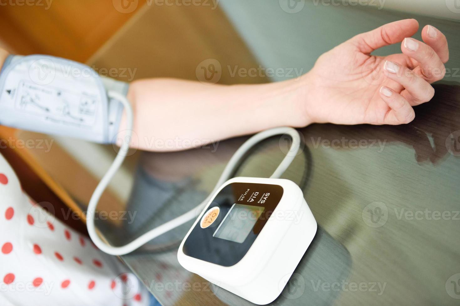 Woman measuring her own blood pressure at home. photo